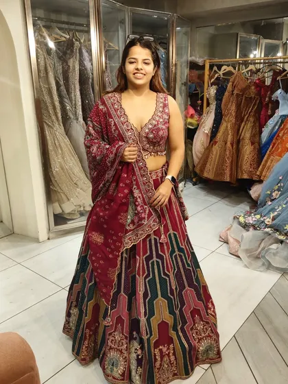 A happy client trying on a vibrant multi-color lehenga. The mix of patterns and colors makes it a perfect choice for a lively Mehendi or Sangeet event.