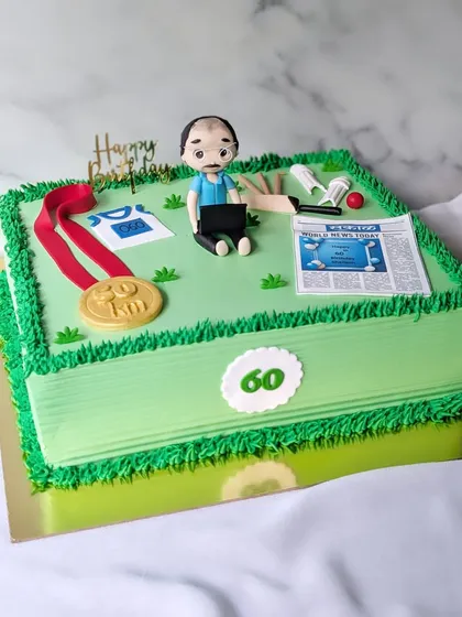 This retirement cake was designed for the editor of Sakal newspaper, celebrating his 60th birthday and career. The design incorporates all his passions: a figurine working on his laptop, an edible newspaper, a marathon medal, and a cricket ball, all set on a field of green buttercream.