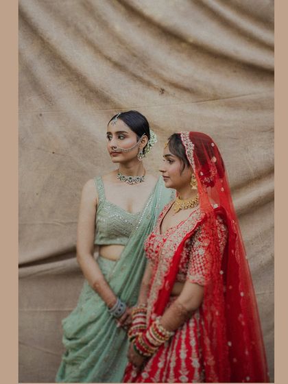 A beautiful portrait of the bride with her sister or bridesmaid. The contrast between the red and mint green outfits creates a visually stunning image that celebrates sisterhood.