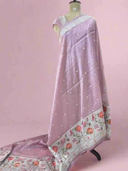 A beautiful pastel lilac tissue saree with a colorful woven Paithani border and delicate butis all over.
