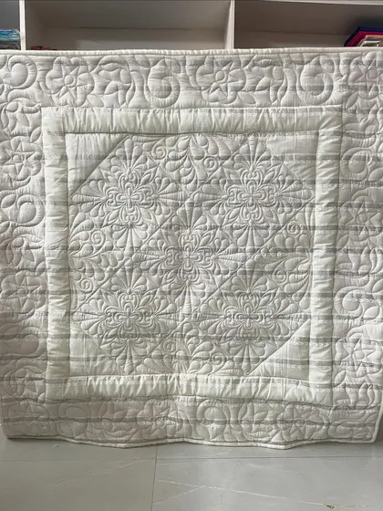 A beautiful all-white baby quilt, where the intricate custom quilting is the star of the show. This is a great example of a wholecloth quilt.