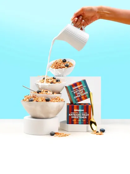 A creative shot featuring a tower of cereal bowls with milk being poured from above. The clean, bright blue background and minimalist styling make this a modern and eye-catching way to showcase a breakfast product.