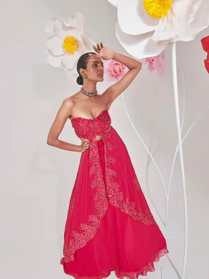 Another angle of a red cutout gown, showcasing the full silhouette and intricate embroidery. The model's pose was directed to create a sense of drama and confidence, highlighting the modern design of the dress.