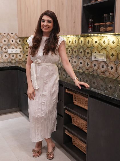 Esha Bahl in her Bali-inspired kitchen. The design combines dark Meteor Oxide laminate with a patterned backsplash and wicker baskets for a warm, eclectic, and personal feel.