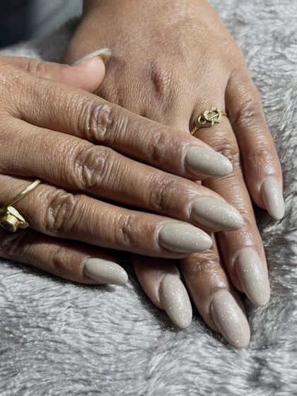 Your nails should always match your vibe. This beautiful set of long, almond-shaped extensions features a shimmery, sandy beige polish for a neutral yet glamorous look.
