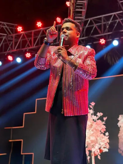 On stage in a dazzling red sequin jacket, pointing to the crowd. This is me in my element, directing the energy and making sure everyone is part of the moment.