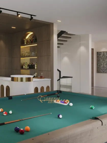 An elegant game room designed for the perfect balance of play and relaxation. The space features a pool table, a sleek home bar with arched detailing, and a view of the floating staircase.