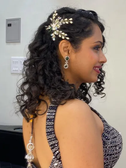 A side view of the elegant half-up hairstyle, perfect for showcasing both her curls and the beautiful hairpiece.