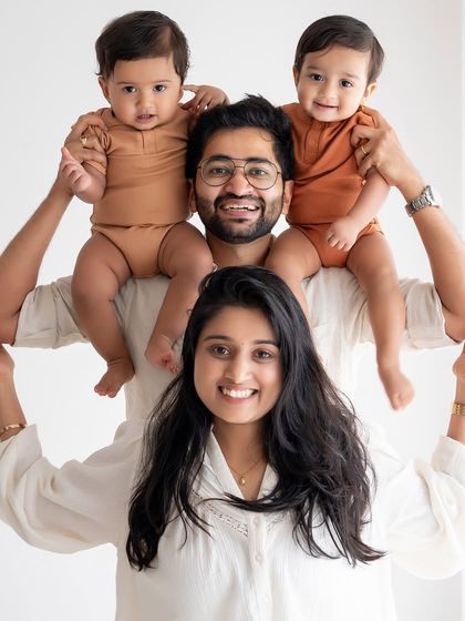 A creative family portrait with the parents holding up their twin boys.