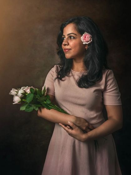 This portrait uses a simple bouquet of roses and a painterly background to create a soft, romantic mood. The subject's gaze is directed away from the camera, inviting the viewer to wonder about her thoughts. It’s a simple yet effective storytelling image.