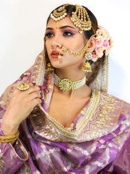 A stunning bridal portrait. The combination of the lavender outfit, floral hair, and dramatic makeup creates a truly memorable look.