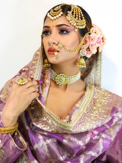 A stunning bridal portrait. The combination of the lavender outfit, floral hair, and dramatic makeup creates a truly memorable look.