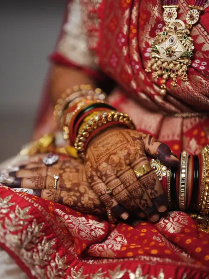A beautiful shot of the bride's hands, adorned with bangles, showcasing the intricate backhand mehendi that complements her custom palm design.