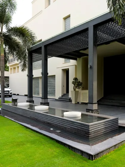 A minimalist water feature runs alongside the home's entrance, reflecting the clean lines of the architecture. This design uses water to create a sense of tranquility and separation between the driveway and the main living areas.