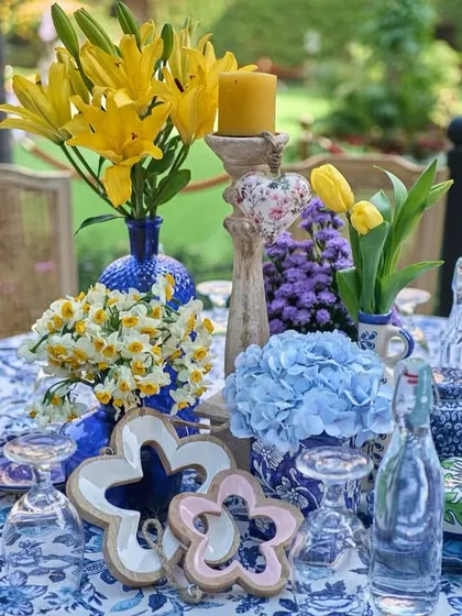 A stunning tablescape combining blue and white printed linens with bright yellow lilies and tulips, creating a cheerful and elegant look for a daytime lunch.