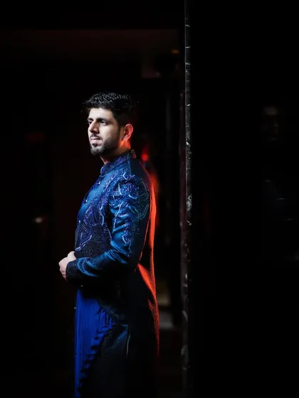 A moody and artistic portrait of the groom, with a red backlight creating a cool effect.