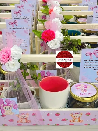 A detailed view of the pink teddy bear return gift, showing the personalized thank you card and the colorful mug inside.
