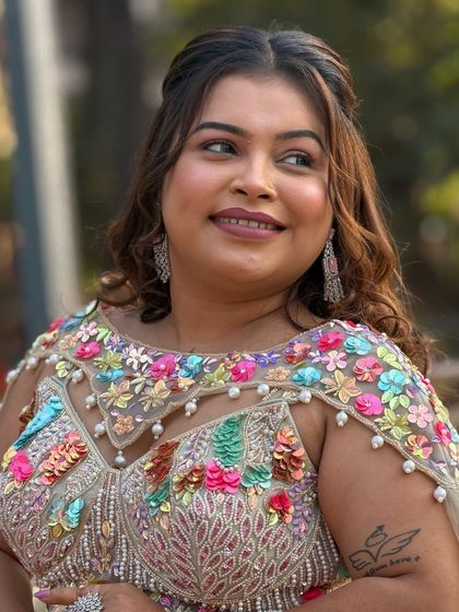 This client is ready for her event with a modern half-up hairstyle. The soft curls add volume and movement, complementing her colorful and contemporary outfit.