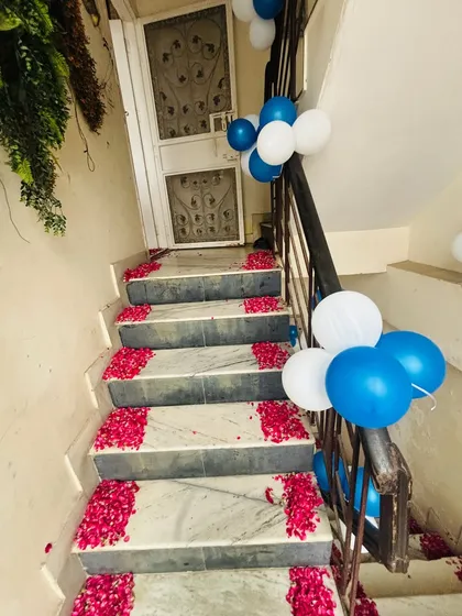 The staircase is decorated with blue and white balloon bunches and rose petals on each step for a baby boy's welcome.