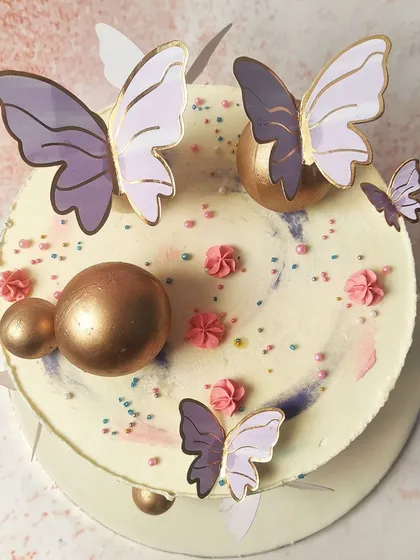 An overhead shot capturing the artistic arrangement of butterflies and golden balls on this unique cake.