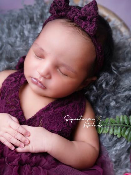 A duplicate of image 25, a beautiful portrait of a newborn in a rich purple dress.