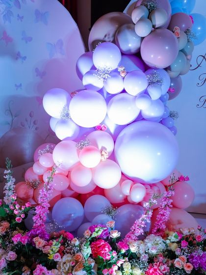 A beautiful cascade of pink, purple, and white balloons mixed with fresh flowers. This combination of textures creates a soft, organic, and luxurious feel perfect for an enchanted garden party.