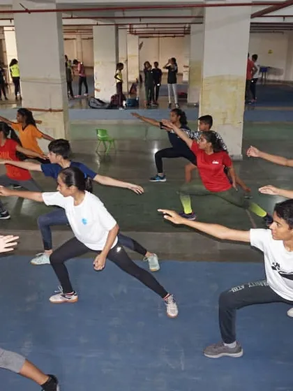 A group of fencers in a deep lunge position during a training session. This foundational move is practiced relentlessly to build strength, flexibility, and perfect form.