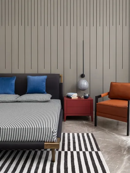 We love to have fun with design, as seen in this bedroom with bold black-and-white stripes on the rug and bedding. The vibrant red nightstand and tan leather chair add playful yet sophisticated pops of color.