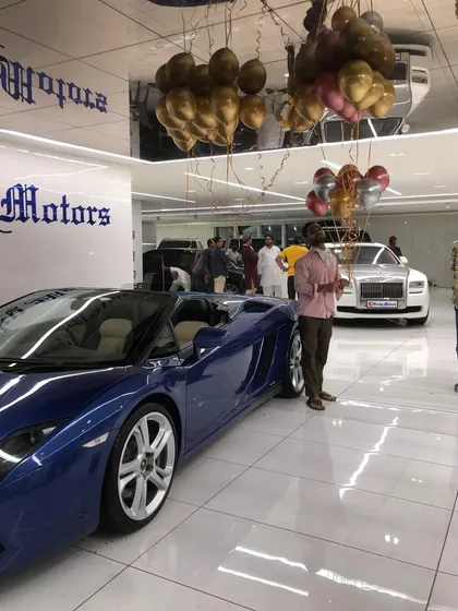 A wide shot of the Lucky Motors showroom during their anniversary event. The ceiling is filled with metallic helium balloons, creating a festive atmosphere throughout the entire space for guests and staff to enjoy.