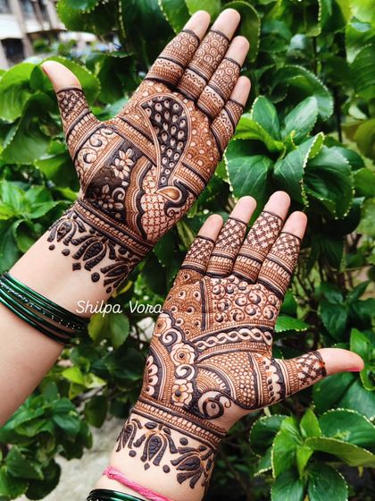 A gorgeous peacock design where the bird's form flows across the palm, complemented by intricate patterns on the fingers.