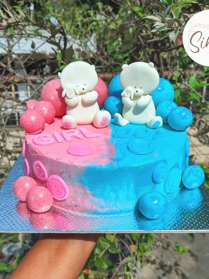 The cutest baby shower cake for twins. This square cake is split down the middle in pink and blue, with two adorable white teddy bears and matching baubles for a "boy or girl" theme.