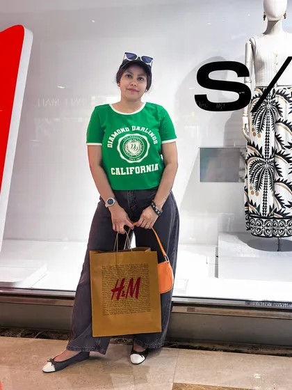 Posing with a shopping bag outside a store in the same casual outfit.