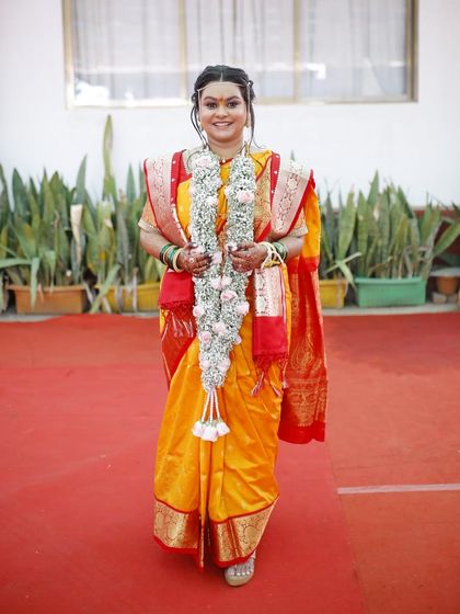 The bride looking radiant as she walks down the aisle. The yellow and red saree for the main ceremony is a classic choice, and the makeup complements it perfectly.
