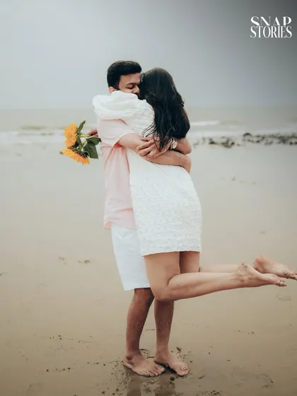 A joyful, candid moment of the couple embracing on the beach, capturing the fun and carefree spirit of their relationship.