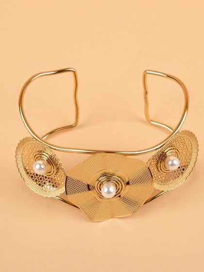 A statement gold-tone floral cuff bracelet, shot on a clean, neutral background to emphasize its design.