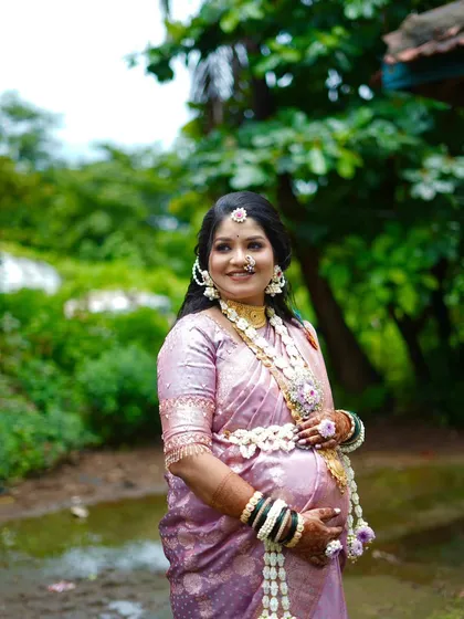 A smiling mom-to-be wearing a floral kamarband (waistband) and necklace set. I design these pieces to be comfortable and adjustable for the perfect fit.