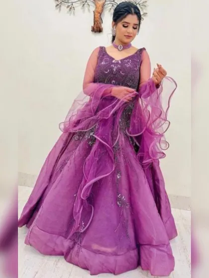 A vibrant purple gown with a ruffled dupatta and embellished bodice. This is a bold and stylish rental choice for anyone looking to stand out at a party or sangeet.