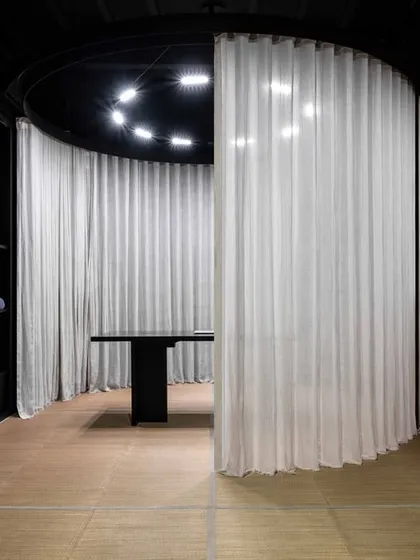 Here, the motorized curtain begins to part, offering a glimpse of the work desk and consultation area within the pod. This dynamic element allows the space to be reconfigured, creating either an open gallery or a series of intimate, private zones.