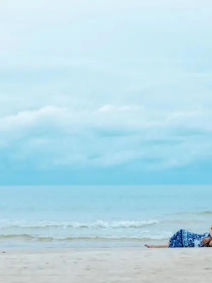 A peaceful moment as the couple relaxes on the sand, looking out at the ocean. This wide shot emphasizes the serene and expansive beauty of the beach location.