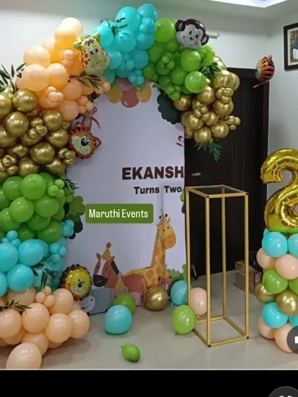 A modern jungle theme for Ekansh's second birthday, using a stylish arch of retro-colored balloons in green, gold, and peach, complete with a backdrop and animal figures.