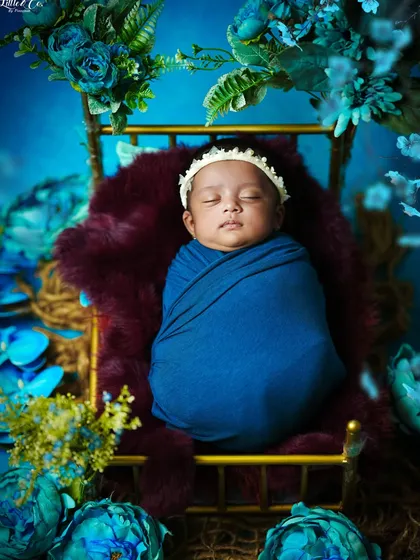 A wider angle of the blue floral setup, showing the full arrangement and the cozy, secure way the baby is swaddled.