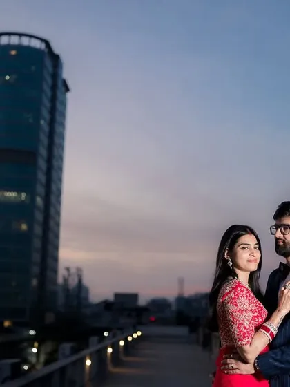 Your story set against the city's evening glow. This cinematic portrait on a rooftop uses the urban landscape and twilight sky to create a dramatic and modern pre-wedding photograph.