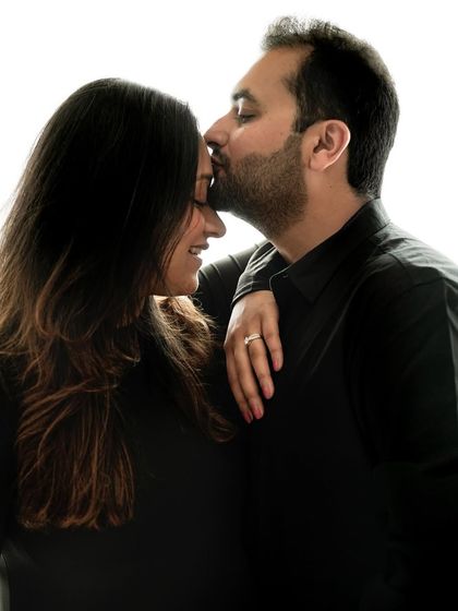 Close up on a tender forehead kiss, showcasing the deep affection and partnership during the pregnancy journey.