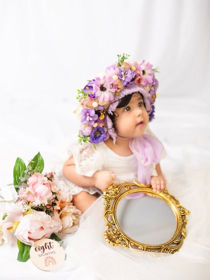 This little one is looking at her reflection in a vintage mirror, a sweet moment from her eight-month milestone session.
