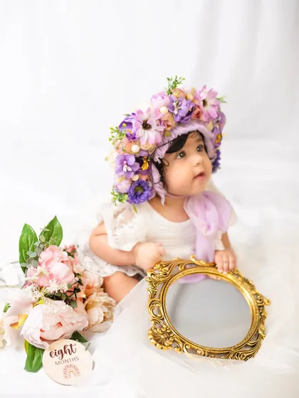 This little one is looking at her reflection in a vintage mirror, a sweet moment from her eight-month milestone session.