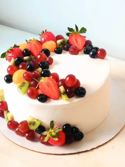 A simple white buttercream cake provides the perfect backdrop for a cascade of colorful fresh fruits. I used strawberries, kiwis, and a mix of red and black grapes for this design.