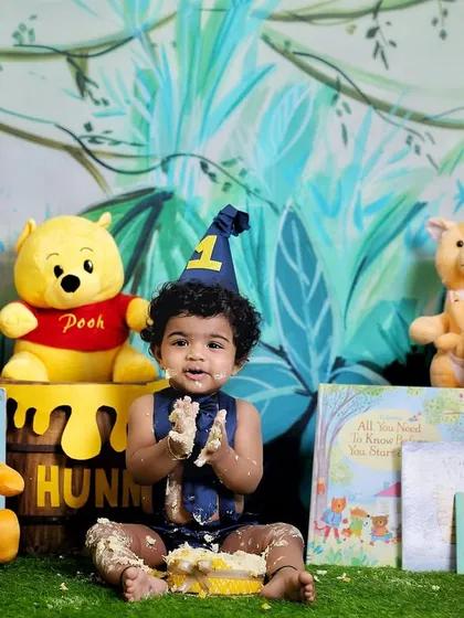 The aftermath of a fun Winnie the Pooh themed cake smash. Surrounded by his favorite characters, this little one is clapping his hands, covered in cake and happiness.