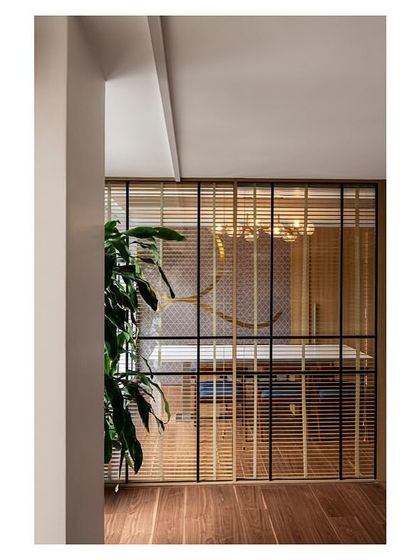 A private dining area within the main dining zone of the IHCL office. A metal and glass partition provides separation, while repurposed furniture and new decorative lighting create an intimate setting.