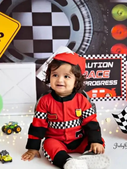 A happy smile from the birthday boy in his racing suit and cap. He's all set to celebrate his big day in style.