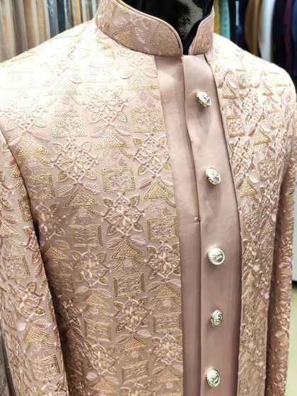A close-up of the dusty rose open sherwani, highlighting the detailed embroidery and the large, elegant buttons that complete the look.